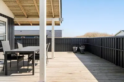 a wooden deck with a table and chairs on a house at 182-Harboore-Vejlby-Klit-153-a in Harboør