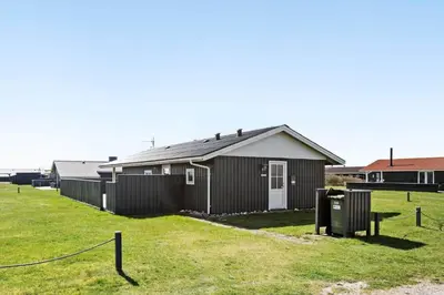 a building with a fence in front of a yard at 182-Harboore-Vejlby-Klit-153-a in Harboør