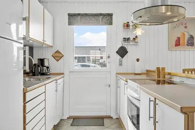 a kitchen with white cabinets and a large window at 204-Harboore-Vejlby-Klit-33 in Harboør
