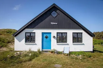a black and white house with a blue door at 276-Harboore-Doblervej-2 in Harboør