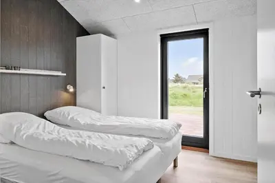 two beds in a room with a large window at 260-Harboore-Strandvejen-158-C in Harboør