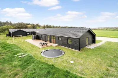 a black house with a playground in a field at 260-Harboore-Strandvejen-158-C in Harboør