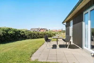 a patio with two chairs and a table on a lawn at 148-Harboore-Lucievej-6-a in Harboør