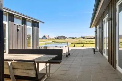 a patio with a bench and a ping pong table at 148-Harboore-Lucievej-6-a in Harboør