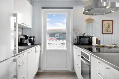 a kitchen with white cabinets and a door with a window at 281-Harboore-Vejlby-Klit-27 in Harboør
