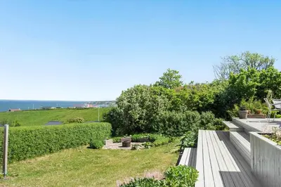 a wooden bench in a garden with a view of the ocean at G302-Lemvig-Skovstjernevej-2 in Lemvig