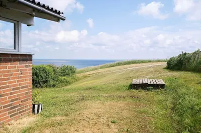 a bench sitting on the side of a field with the ocean at G192-Lemvig-Violvej-92 in Lemvig