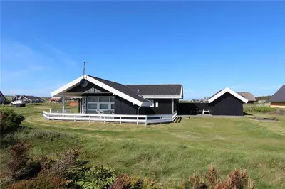 a black and white house on a grass field at 307-Harboore-Fourmivej-55 in Harboør