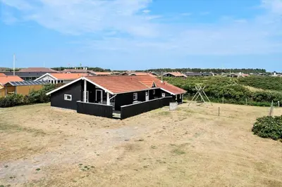 a black house with a red roof on a field at 121-Harboore-Vejlby-Klit-173-a in Harboør