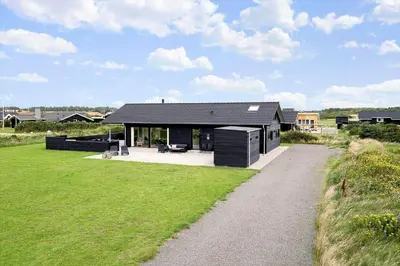 a house with a black roof on a grass field at 237-Harboore-Neerlandiavej-17 in Harboør
