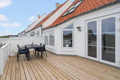 a wooden deck with a table and chairs on a house at 325-Harboore-Skalvej-4-c in Harboør