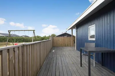 a wooden deck with a table on the side of a building at 138-Harboore-Neerlandiavej-6 in Harboør