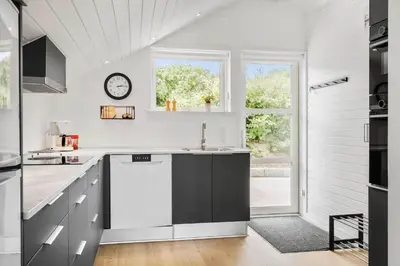 a white kitchen with a sink and a clock at G246-Lemvig-Skovstjernevej-57 in Lemvig
