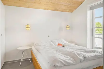 a white bedroom with a bed and a table at G217-Lemvig-Violvej-17 in Lemvig