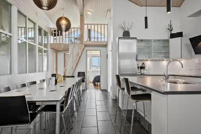 a kitchen with a long counter with chairs and tables at 305-Harboore-Arcticvej-6 in Harboør