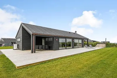 a black house with a wooden deck in a field at G307-Lemvig-Bynkevej-7 in Lemvig