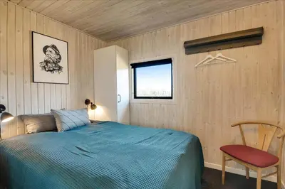 a bedroom with a bed and a chair and a window at 100-Harboore-Vejlby-Klit-51 in Harboør