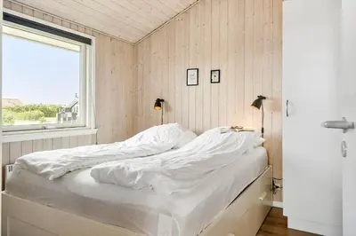 a bed with white sheets in a room with a window at 212-Harboore-Neerlandiavej-62 in Harboør