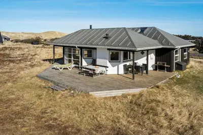 a small house with a deck in a field at 378-Harboore-Gloryvej-43 in Harboør