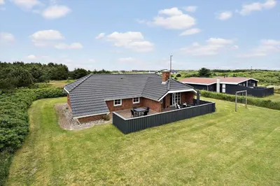 a house with a black roof on a grass field at 143-Harboore-Vejlby-Klit-15 in Harboør