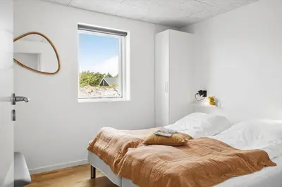 a bedroom with a bed with white walls and a window at 375-Harboore-Gloryvej-14-A in Harboør