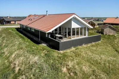 a small house on top of a grassy hill at 194-Harboore-Vejlby-Klit-309 in Harboør