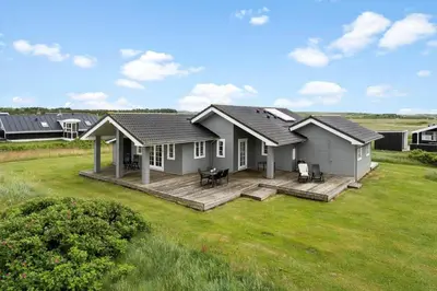 a small house with a deck in a field at 187-Harboore-Neerlandiavej-1 in Harboør