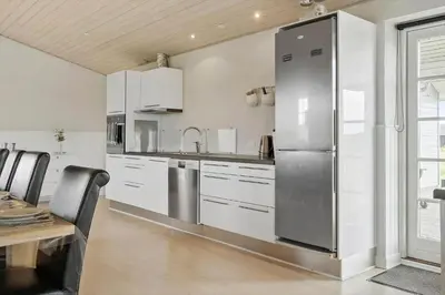 a kitchen with white cabinets and a stainless steel refrigerator at 187-Harboore-Neerlandiavej-1 in Harboør