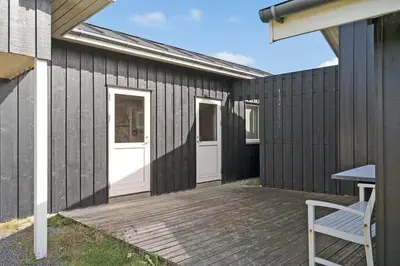 a house with a wooden deck with a white door at 355-Harboore-Gloryvej-14 in Harboør