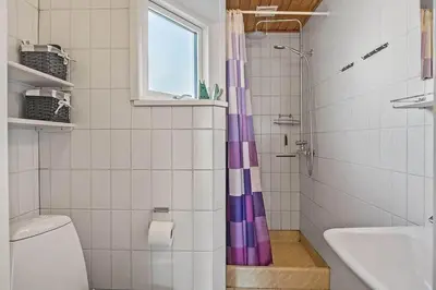 a bathroom with a purple shower curtain next to a toilet at 355-Harboore-Gloryvej-14 in Harboør