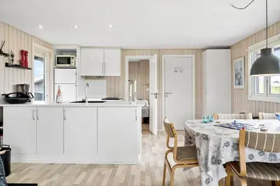 a kitchen and dining room with white cabinets and a table at G305-Lemvig-Porsevej-105 in Lemvig
