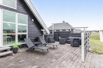 a patio with chairs and a grill and a house at 226-Harboore-Nautilusvej-5 in Harboør