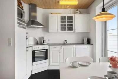 a kitchen with white cabinets and a table with chairs at 323-Harboore-Skalvej-4-a in Harboør