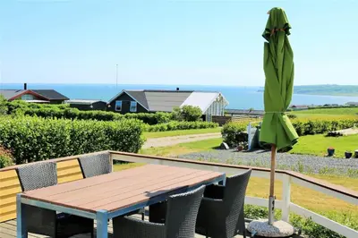 a wooden table with chairs and an umbrella on a deck at G131-Lemvig-Skovstjernevej-31 in Lemvig