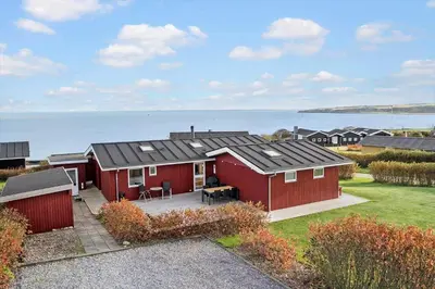 a red house with a patio in front of the ocean at G281-Lemvig-Syrenvej-81 in Lemvig