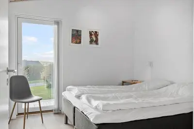 a bedroom with a bed and a chair and a window at G281-Lemvig-Syrenvej-81 in Lemvig