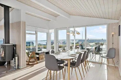 a dining room with a table and chairs and windows at G281-Lemvig-Syrenvej-81 in Lemvig
