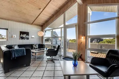 a living room with black furniture and large windows at 102-Harboore-Vejlby-Klit-21 in Harboør