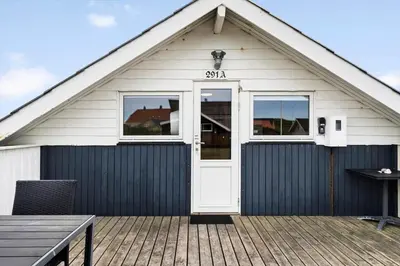 a house with a white door on a wooden deck at 209-Harboore-Vejlby-Klit-291-A in Harboør