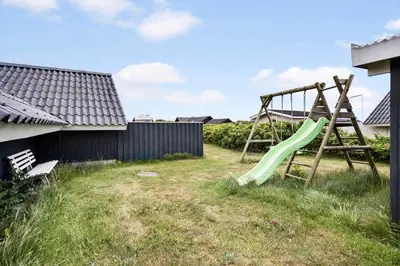 a playground with a green slide in a yard at 209-Harboore-Vejlby-Klit-291-A in Harboør