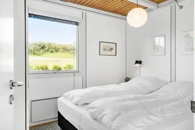a white bedroom with two beds and a window at G120-Lemvig-Gyvelvej-20 in Lemvig