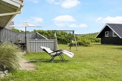a chair sitting in a yard with a swing at 134-Harboore-Karolinevej-8 in Harboør