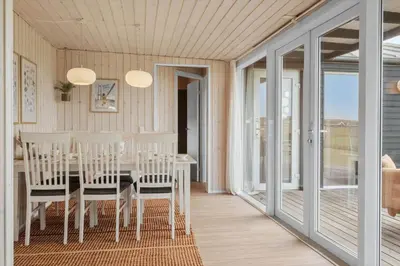 a dining room with a table and chairs and sliding glass doors at 227-Harboore-Bjergehusvej-4 in Harboør