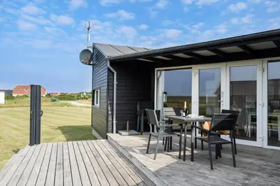 a patio with a table and chairs on a deck at 227-Harboore-Bjergehusvej-4 in Harboør