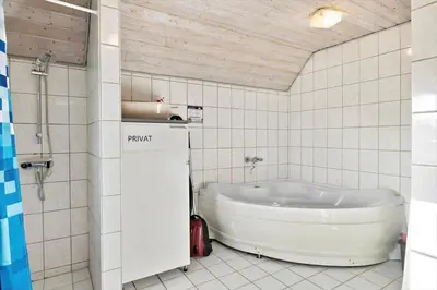 a bathroom with a tub in a tiled room at 377-Harboore-Fourmivej-56 in Harboør