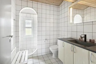 a white tiled bathroom with a toilet and a sink at 803-Harboore-Merchantvej-9-A in Harboør
