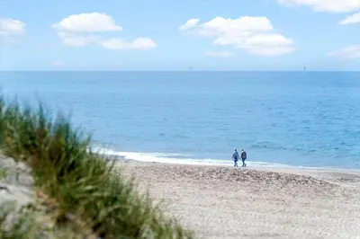 two people walking on a beach near the ocean at 803-Harboore-Merchantvej-9-A in Harboør