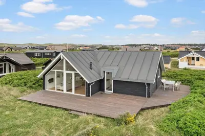 a house with a grey roof and a wooden deck at 805-Harboore-Vejlby-klit-247 in Harboør