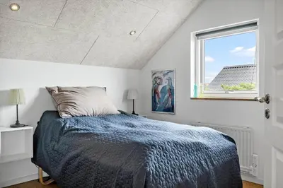 a bedroom with a bed with a blue comforter and a window at 805-Harboore-Vejlby-klit-247 in Harboør