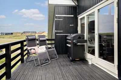 a deck with two chairs and a grill on it at 807-Harboore-Dalevej-9 in Harboør